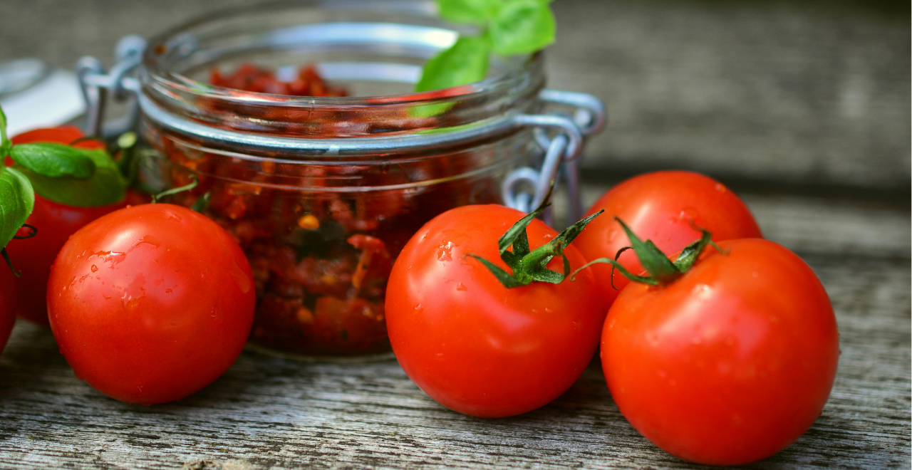 Gros plan sur une tomate rouge vif et brillante au premier plan, avec d'autres tomates légèrement floues en arrière-plan, montrant différentes nuances de maturation